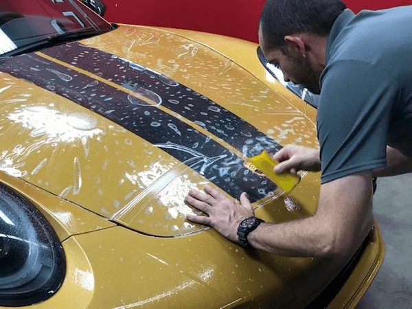 man preserving the paint on a yellow car